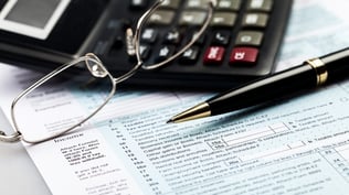 Calculator with a pen and tax documents at invoice factoring company's office